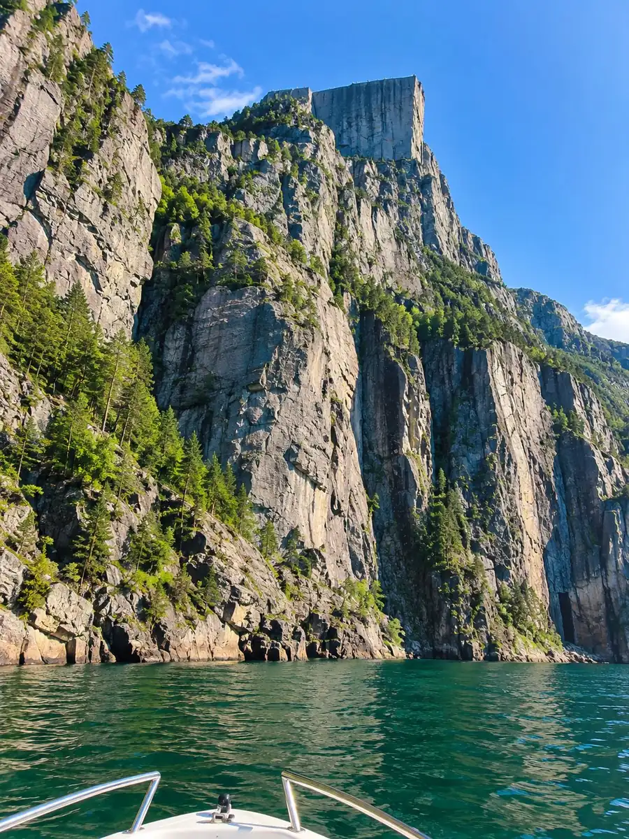 Blick von einem Boot auf die steile Granitfelswand des Preikestolen über dem Lysefjord